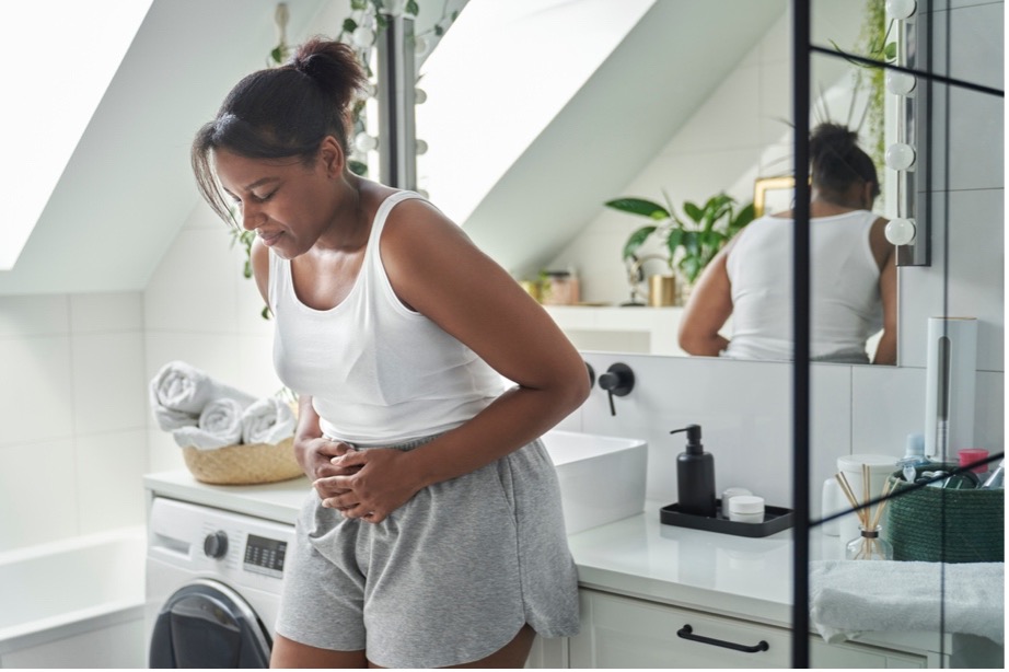 A woman of African-American descent, who is young, is standing in a bathroom and experiencing chronic constipation, rectal prolapse symptoms